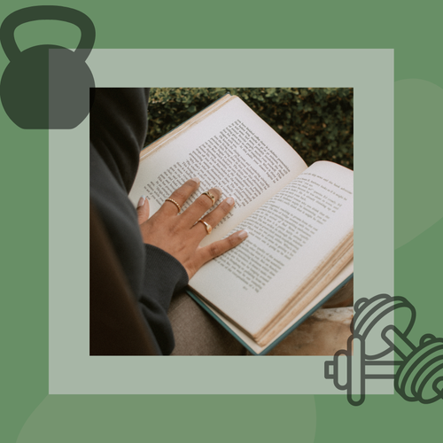 a woman is reading a book and holding a kettlebell.