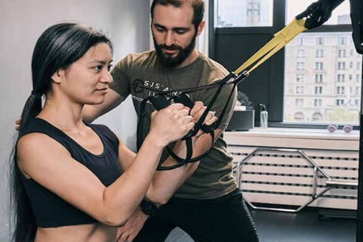 a man and woman doing a trx workout in a gym.