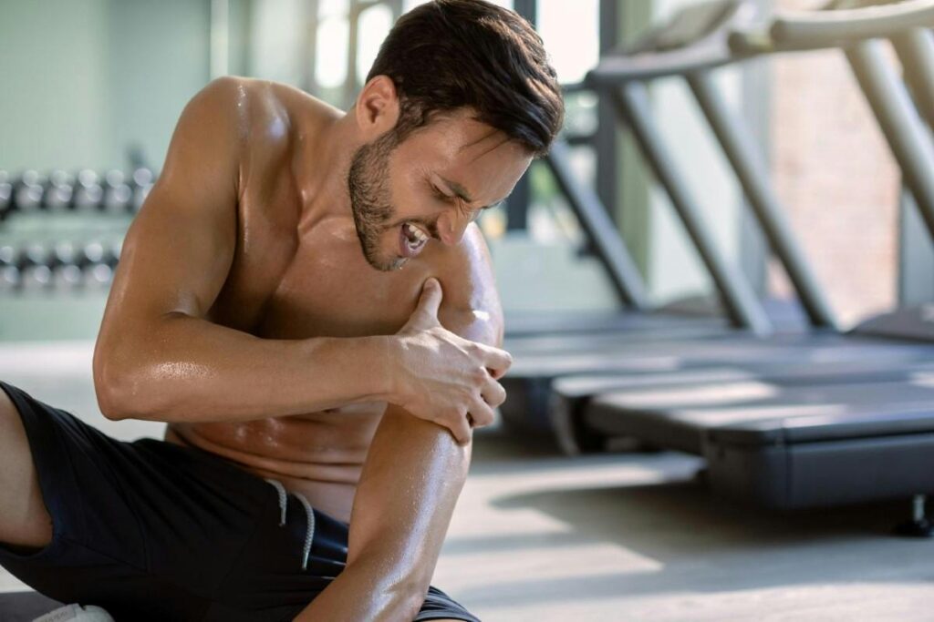 Man experiencing shoulder pain during a workout, potentially requiring physical therapy for recovery and rehabilitation.