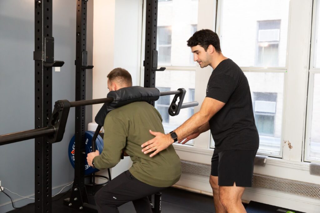 Physical therapist guiding patient through squat exercise to support rehabilitation for hip pain from running.