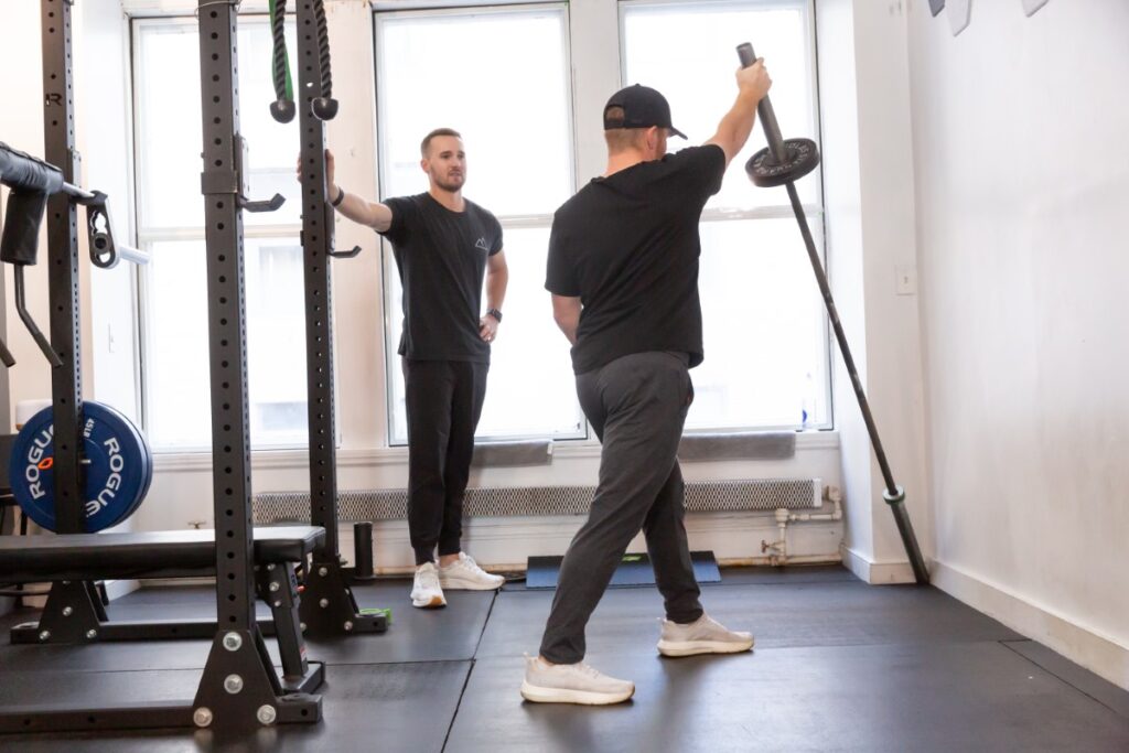 Patient performing shoulder strengthening exercise under therapist supervision as part of physical therapy for shoulder pain.