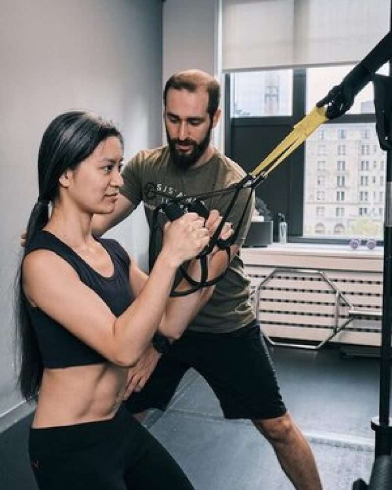 a man and woman doing a trx workout in a gym.